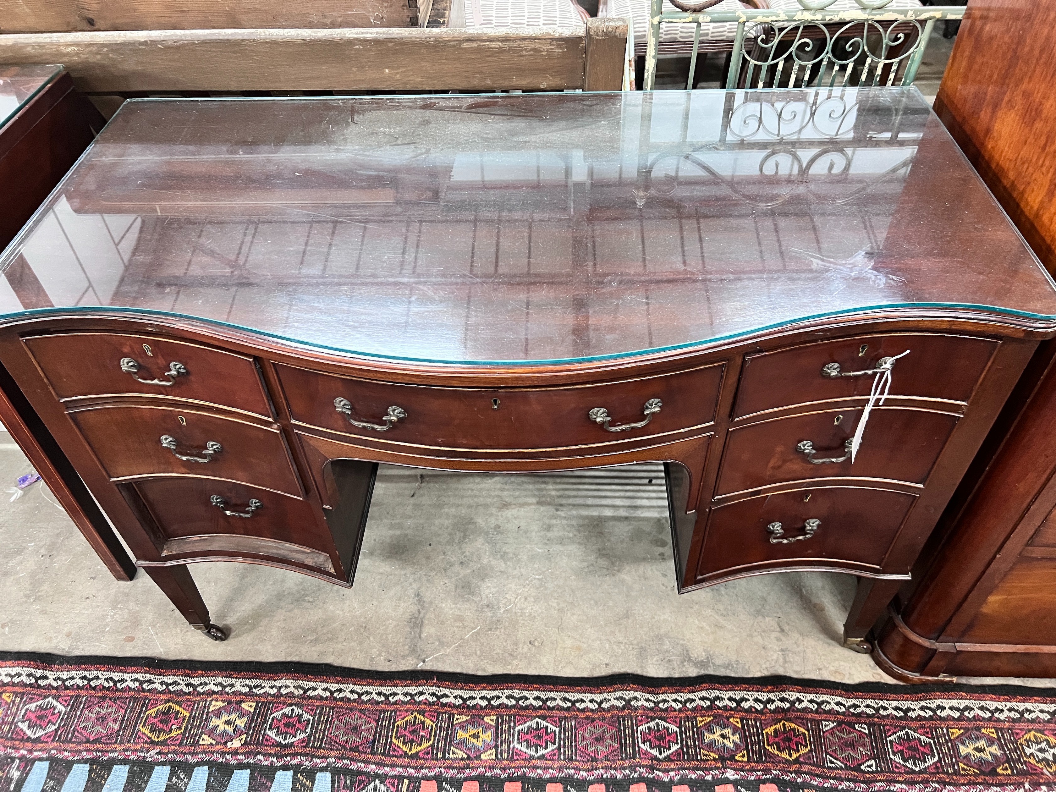 A 1920's serpentine mahogany kneehole dressing table, width 120cm, depth 61cm, height 76cm *Please note the sale commences at 9am.